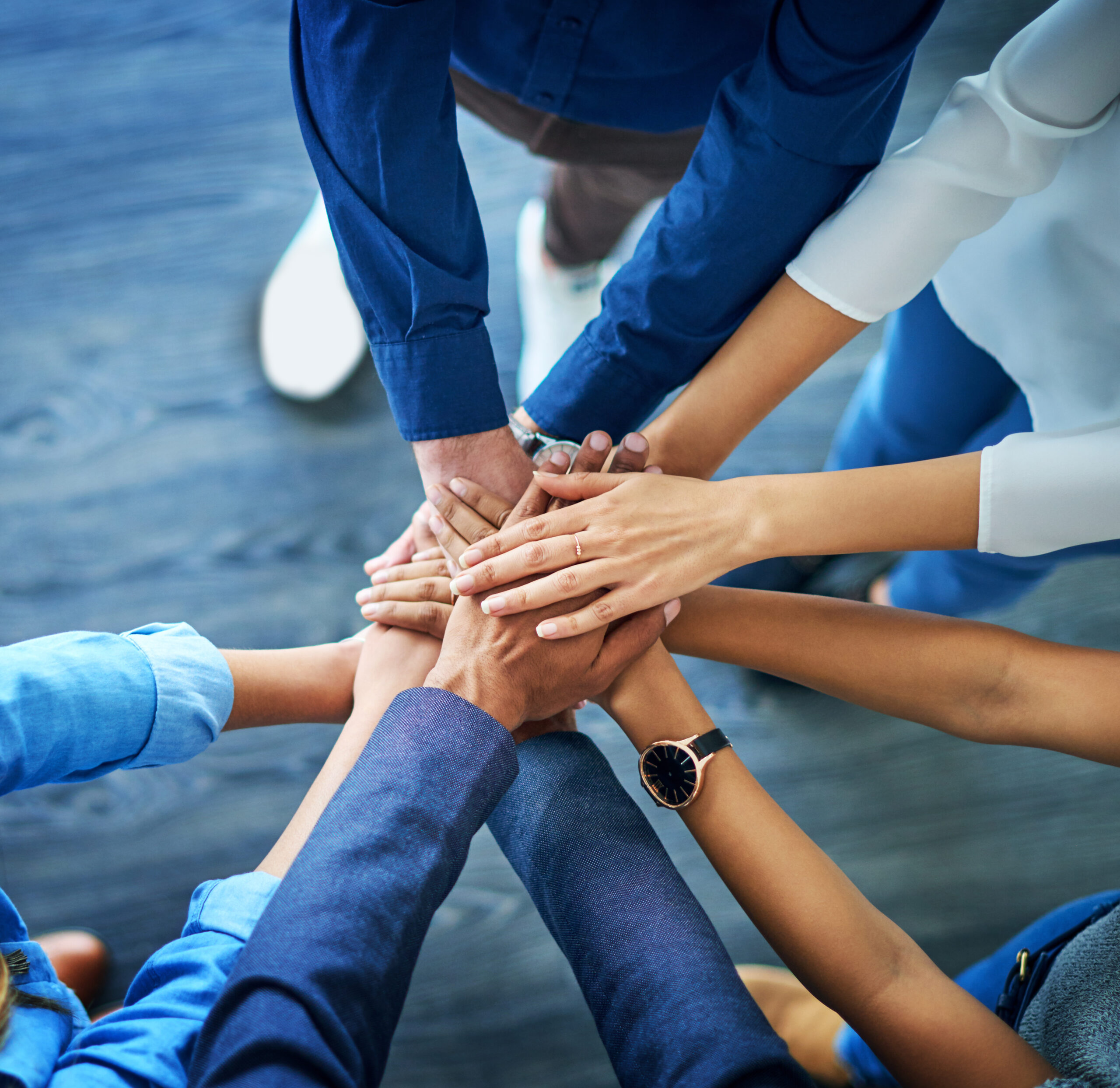 High angle shot of a group unrecognizable businesspeople joining their hands together in unity.
